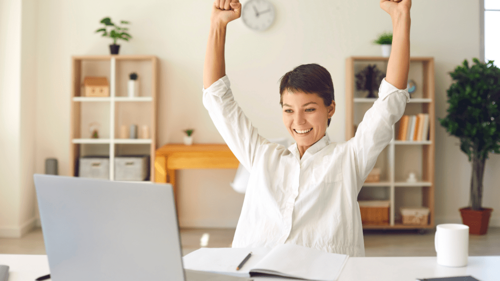 A person sitting at a desk with their arms up