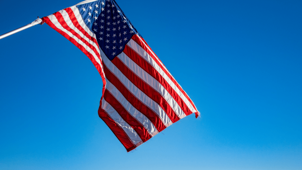 An American flag blowing in the wind against a blue sky