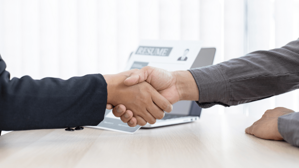 Two business people shaking hands over a laptop