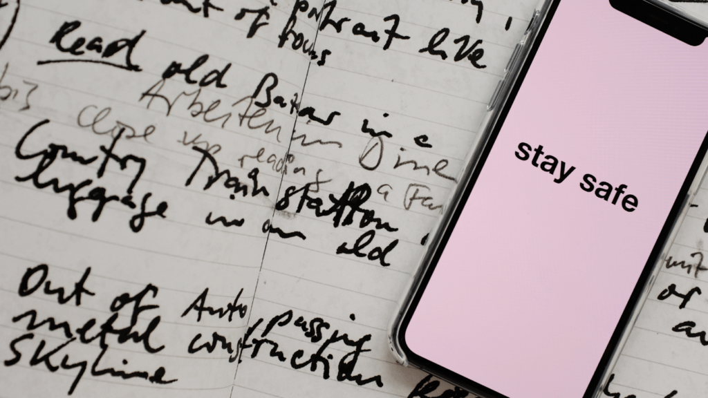 a person's hand holding an iphone in front of a sheet of paper with handwritten notes on it