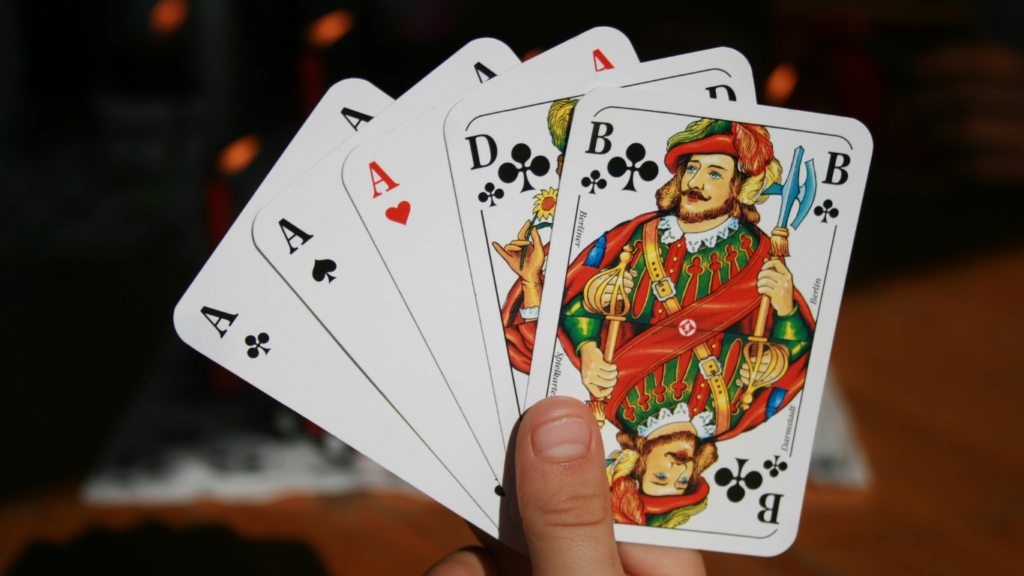 a hand holding four playing cards on a table