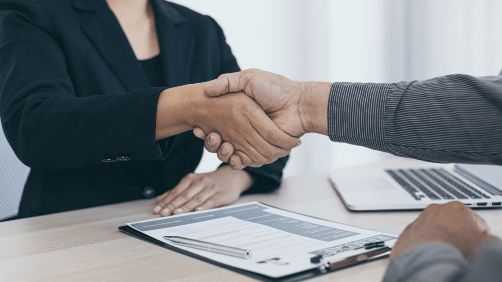 Two business people shaking hands over a laptop