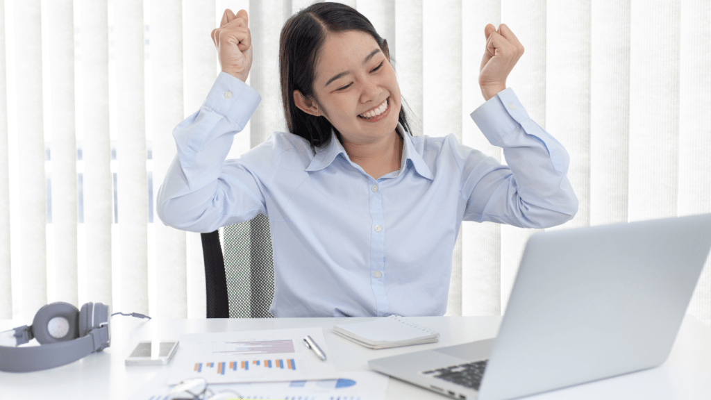 A person sitting at a desk with their arms up