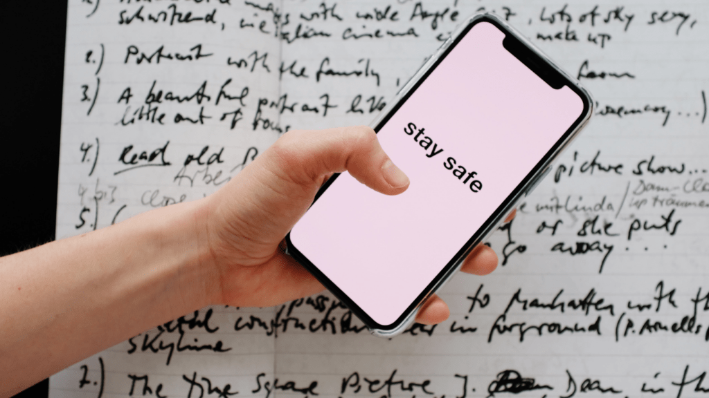 a person's hand holding an iphone in front of a sheet of paper with handwritten notes on it