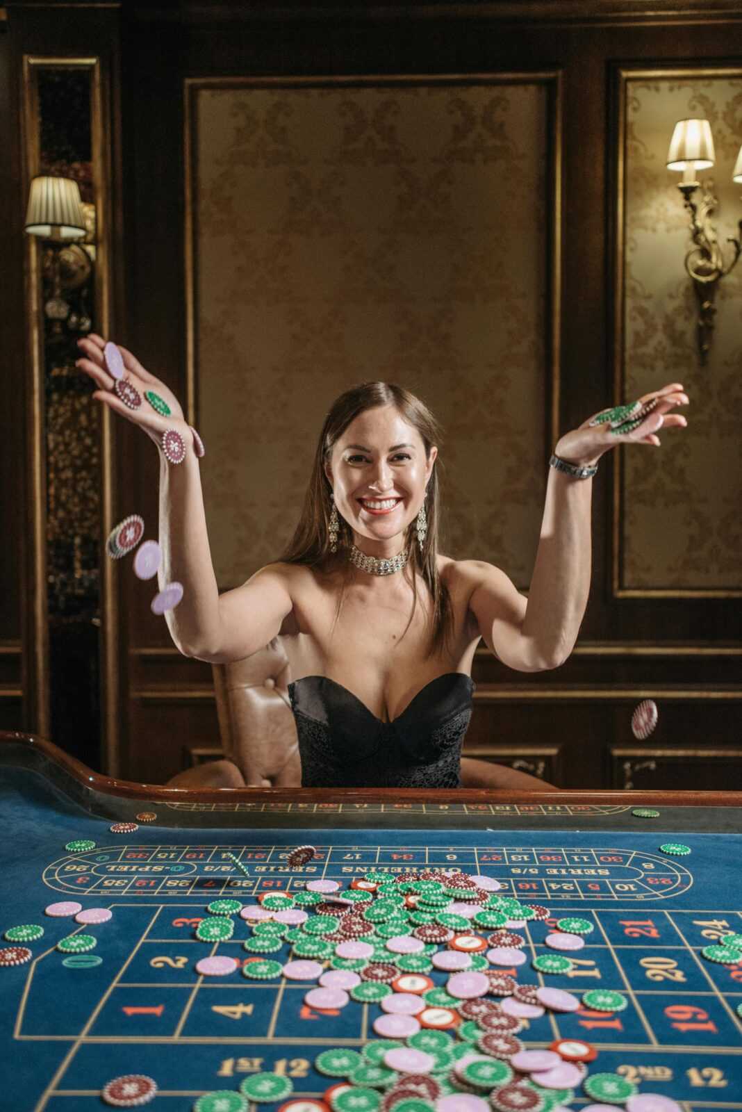 A joyful woman throws chips in triumph at a luxurious casino roulette table.